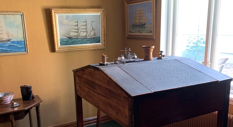 Gammeldags kontor vars väggar är prydda med målningar på skepp.