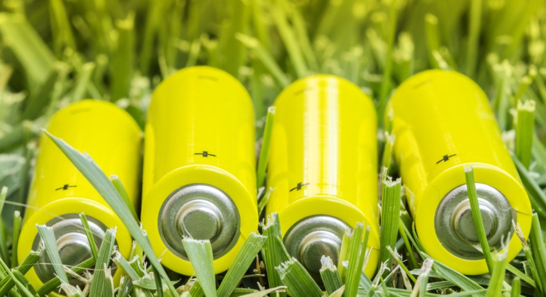 Fyra gulgröna batterier ligger i ett kortklippt grönt gräs.